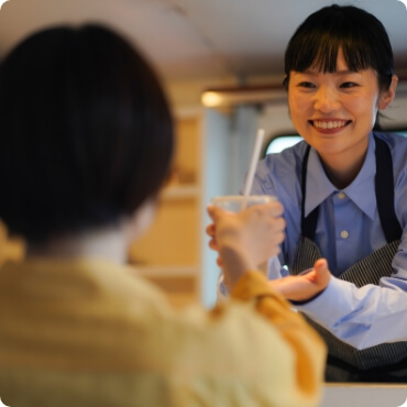 キッチンカーから商品を手渡す女性