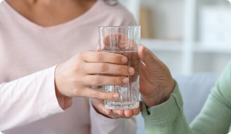 水が入ったガラスのグラスを手に取る男女
